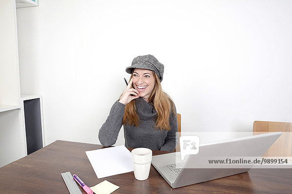Porträt einer lächelnden Frau mit Laptop am Holztisch