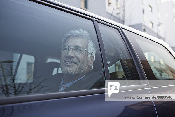 Smiling businessman looking through window of his car
