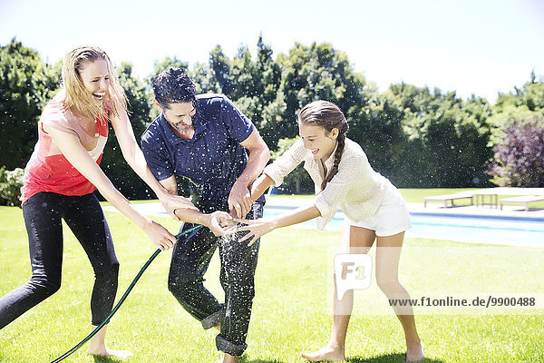 Happy family splashing water with garden hose