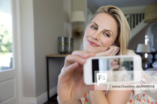 Blonde Frau nimmt Selfie mit Smartphone