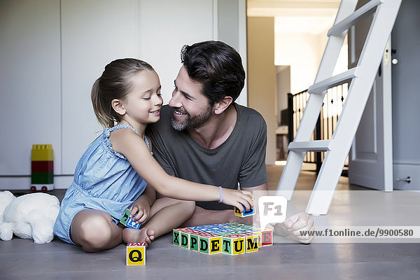 Vater und Tochter spielen mit Bausteinen auf dem Boden