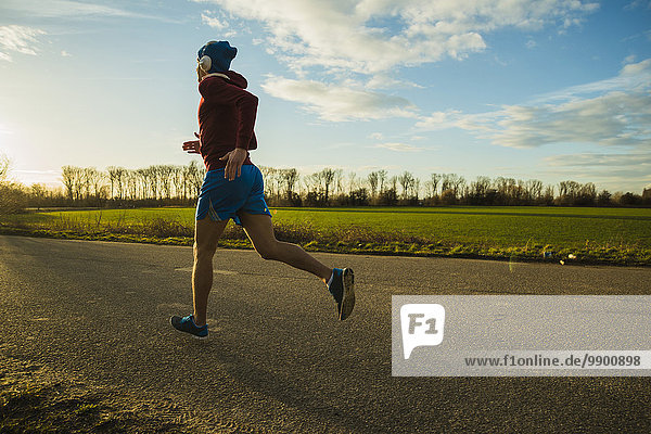 Germany  Mannheim  young man jogging on rural road