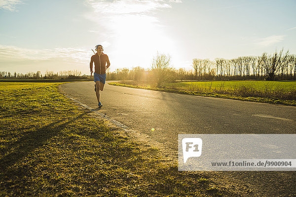 Germany  Mannheim  young man jogging on rural road