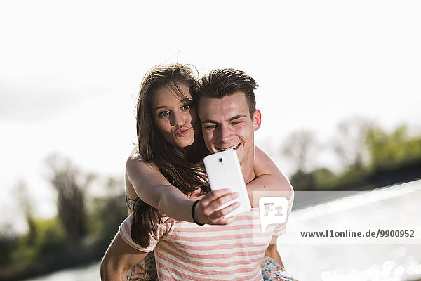 Playful young couple taking selfie outdoors