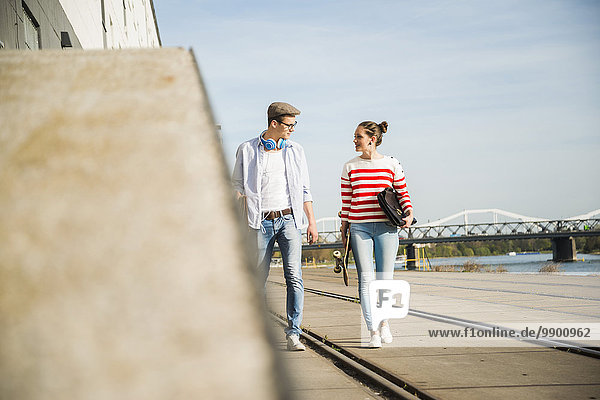 Junger Mann und junge Frau  die am Flussufer spazieren gehen