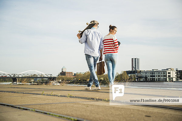 Young man and woman walking at track by the riverside