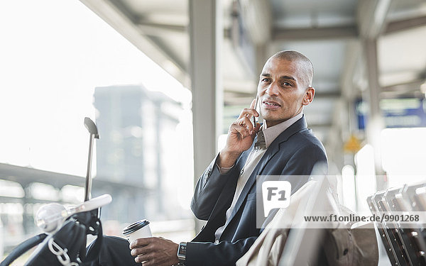 Businessman at the train station talking on smartphone