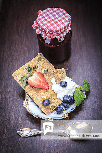 Marmeladenglas  Scheibe Knäckebrot  Quark und Früchte auf Holz