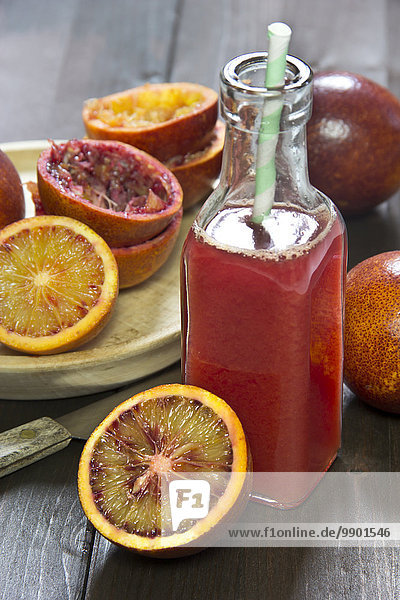 Glass bottle of blood orange juice  whole  sliced and squeezed blood oranges