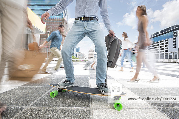 Stadtpendler auf einem Skateboard zwischen einer Menschenmenge