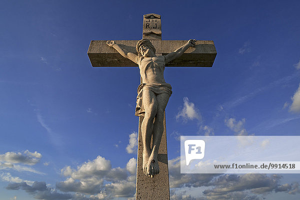 Steinernes Kruzifix gegen blauen Wolkenhimmel  Bayern  Deutschland  Europa