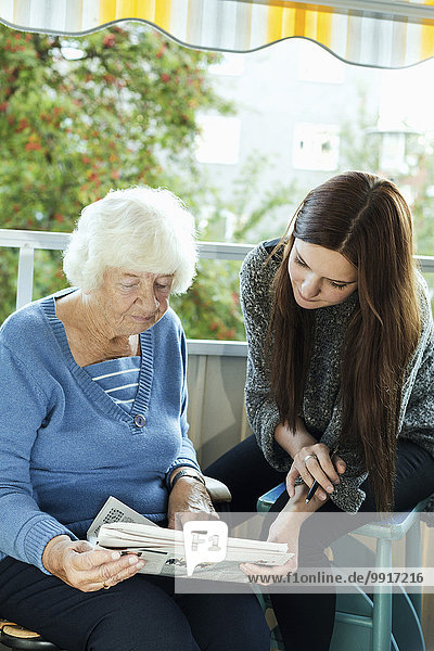 Großmutter und Enkelin beim Zeitungslesen auf der Veranda