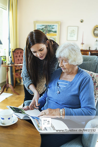 Großmutter und Enkelin lesen zusammen im Wohnzimmer