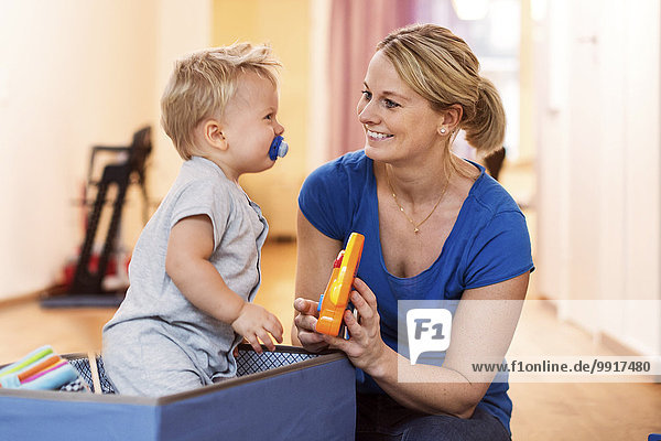 Happy woman playing toys with baby boy at home
