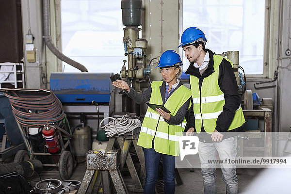 Handwerker mit digitalem Tablett diskutieren in der Fabrik