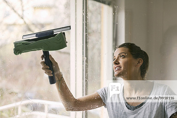 Frau reinigt Glasfenster