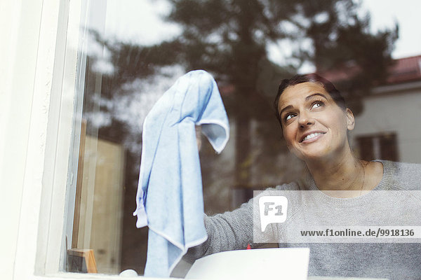 Frau reinigt Glas des Hausfensters
