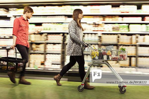 Junges Paar geht im Supermarkt an den Regalen vorbei