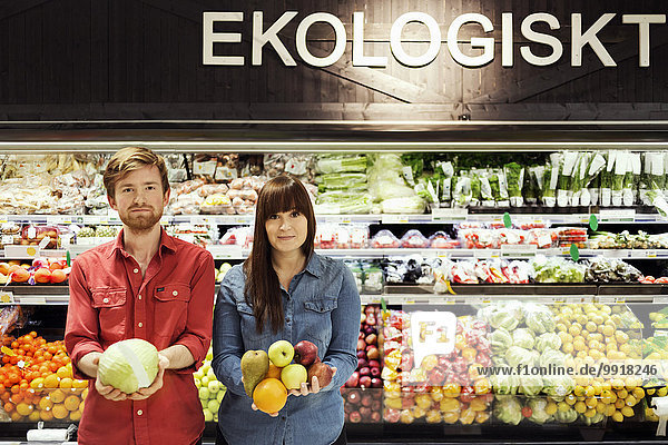 Porträt eines jungen Paares mit frischem Gemüse im Supermarkt
