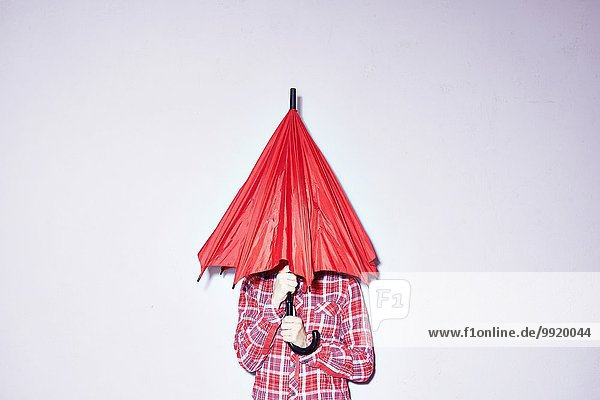 Studio shot of young woman holding red umbrella over her head