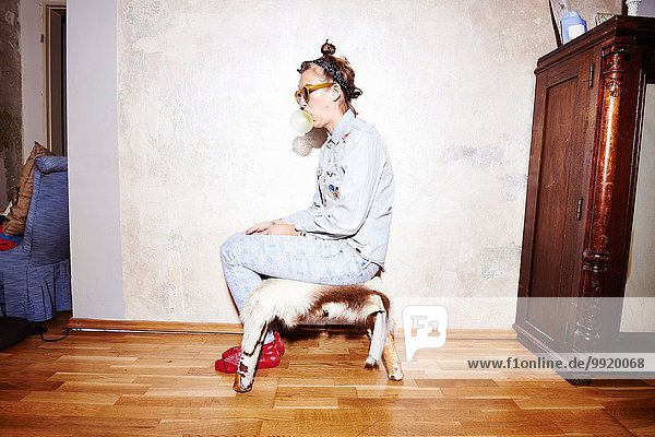 Junge Frau mit Sonnenbrille und Bubblegum auf dem Socken sitzend