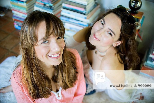 Porträt zweier junger Freundinnen auf dem Boden sitzend