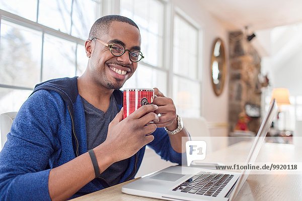 Portrait of mid adult man using laptop at kitchen counter