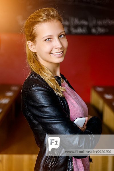 Porträt einer selbstbewussten jungen Frau mit gefalteten Armen im Cafe