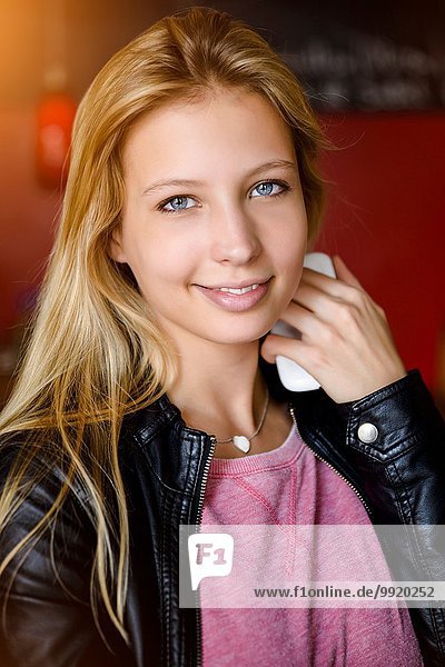 Porträt einer jungen Frau mit Smartphone im Café