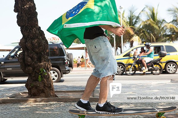 Junger Mann Skateboarding in brasilianischer Flagge  Copacabana  Rio De Janeiro  Brasilien