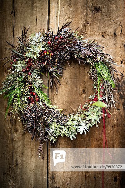 Weihnachtskranz mit Laub und Beeren auf Holztür