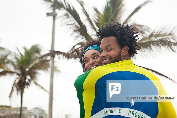 Rückansicht des Paares in brasilianischer Flagge am Strand von Ipanema  Rio De Janeiro  Brasilien