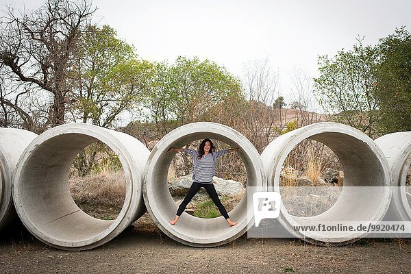Portrait of young woman standing inside concrete pipe in rural landscape