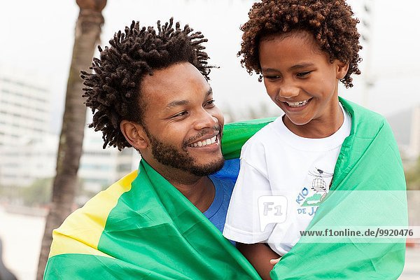 Vater und Sohn mit brasilianischer Flagge am Strand von Ipanema Rio De Janeiro Brasilien