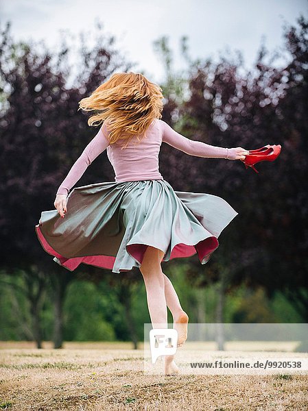 Rear view of young woman dancing and twirling and in park