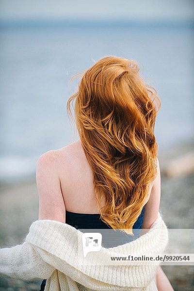 Rückansicht einer jungen Frau mit langen roten Haaren und Blick aufs Meer,  Bainbridge Island,  Washington State,  USA