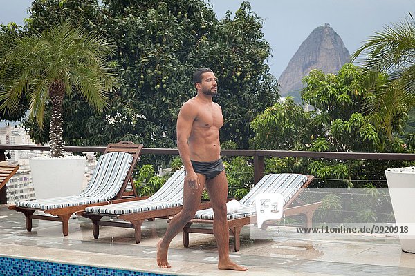 Man by poolside  Sugarloaf Mountain in background  RIo  Brazil