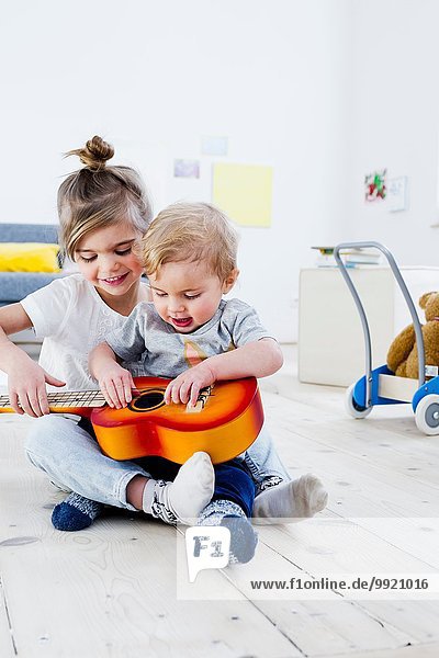 Geschwister spielen zu Hause Spielzeuggitarre