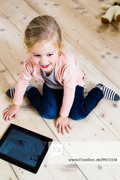 Mädchen mit digitalem Tablett auf Holzboden