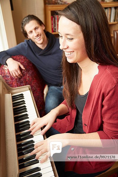 Junge Frau spielt Klavier für ihren Freund