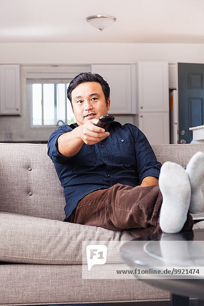 Erwachsener Mann auf dem Sofa mit Fernbedienung