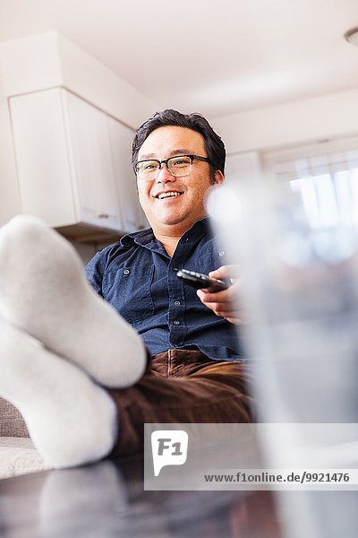 Erwachsener Mann auf dem Sofa fernsehen mit Fernbedienung