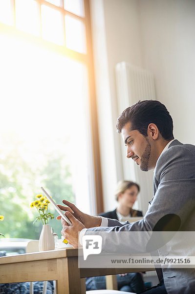Mann mit digitalem Tablett im Café