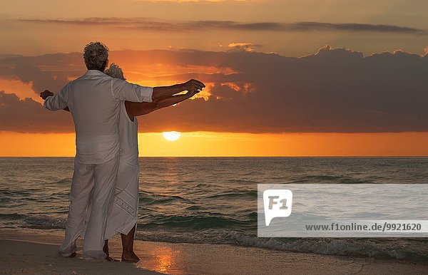 Seniorenpaar am Strand bei Sonnenuntergang