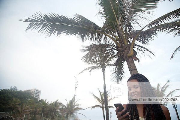 Young women reading smartphone texts on Ipanema beach  Rio De Janeiro  Brazil