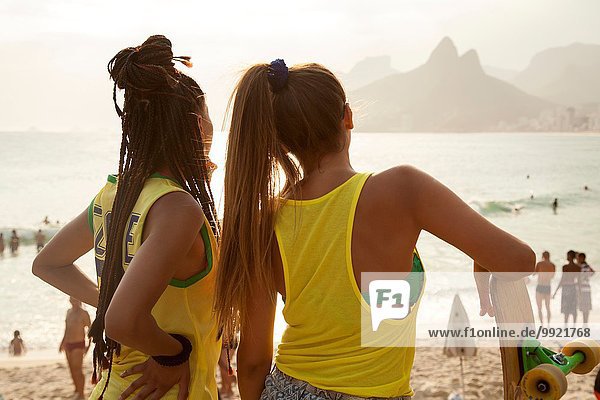 Rear view of two young women looking out over Ipanema beach  Rio De Janeiro  Brazil