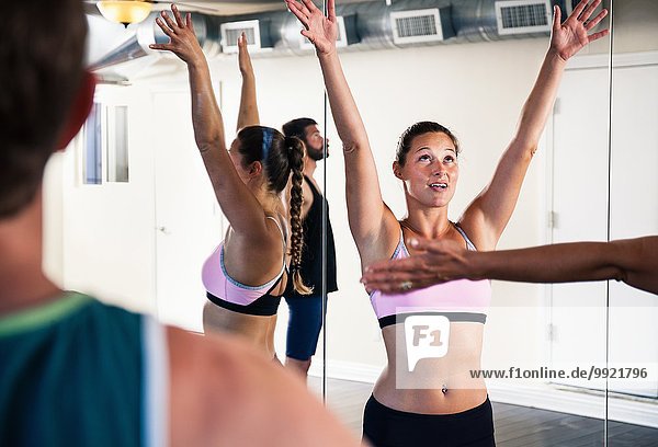 Mittlere erwachsene Frau in der Yogaklasse mit erhobenen Armen