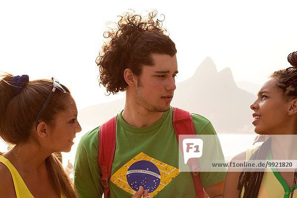 Three young adult friends chatting on Ipanema beach  Rio De Janeiro  Brazil