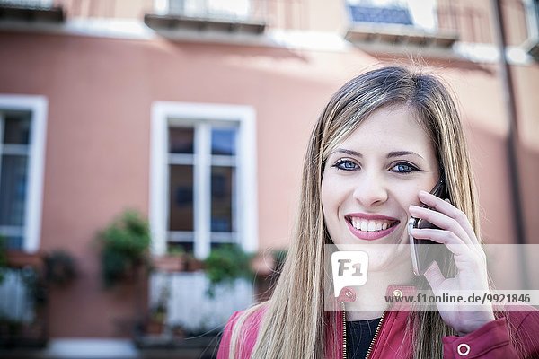 Portrait einer jungen Frau auf der Straße  die auf dem Smartphone spricht  Cagliari  Sardinien  Italien