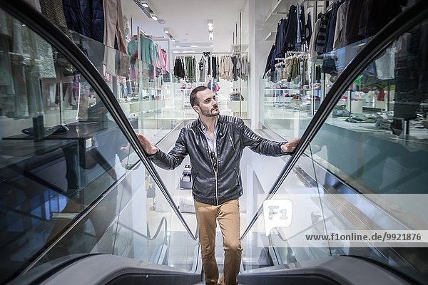 Mittlerer Erwachsener Mann bewegt sich auf Rolltreppe im Einkaufszentrum